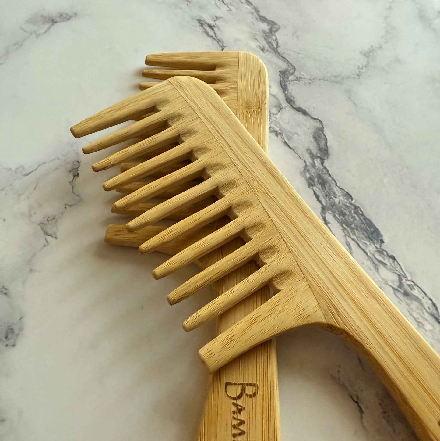 Two Bamboo Detangling Wide Combs on a marble surface