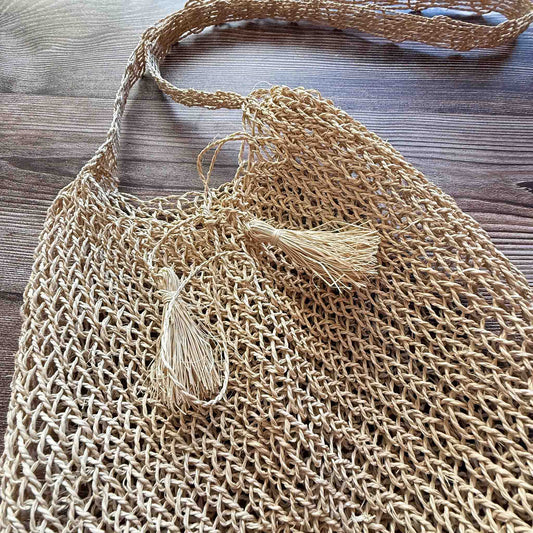 Handwoven Cumare Fiber Mochila with a strap on a wooden surface