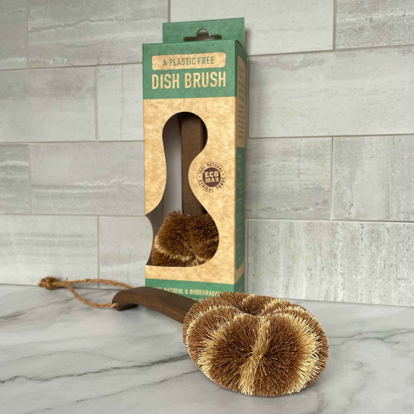 Dish brush with packaging on a marble surface and tiled wall background