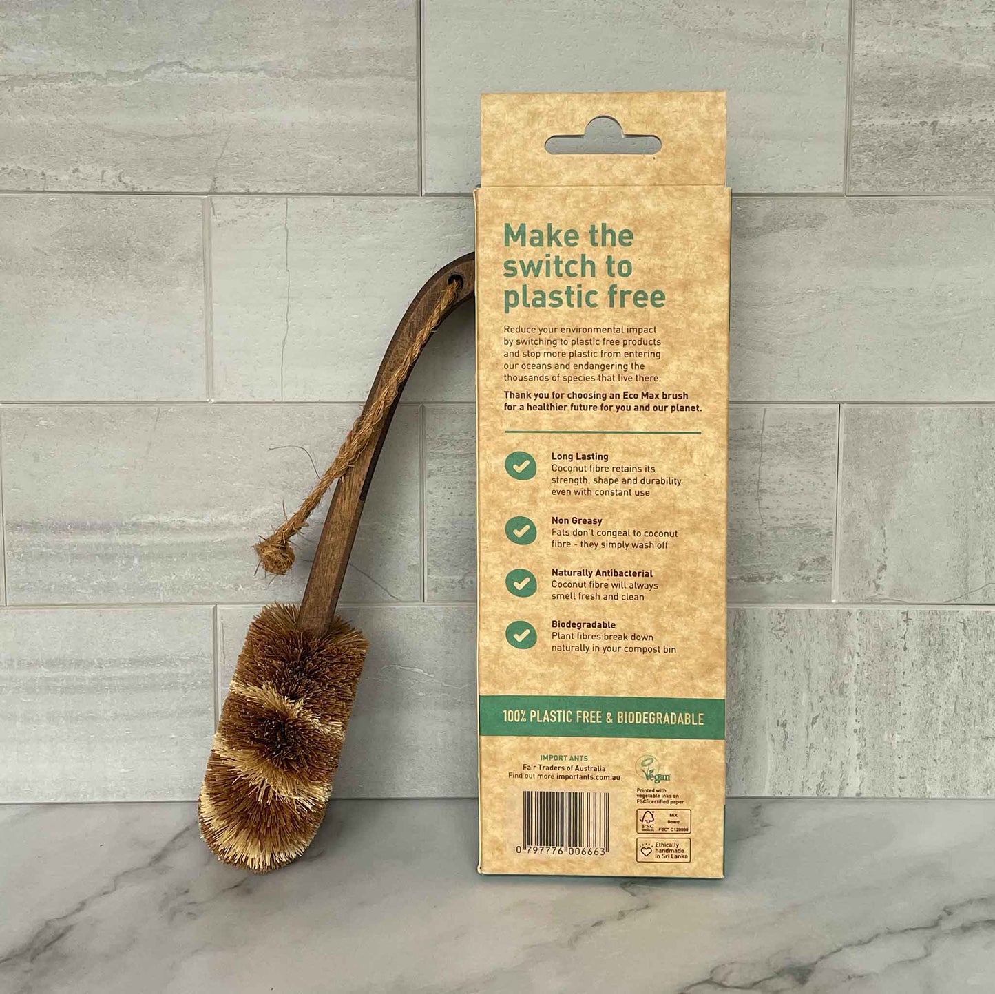 Plastic-free cleaning brush with packaging on a tiled floor