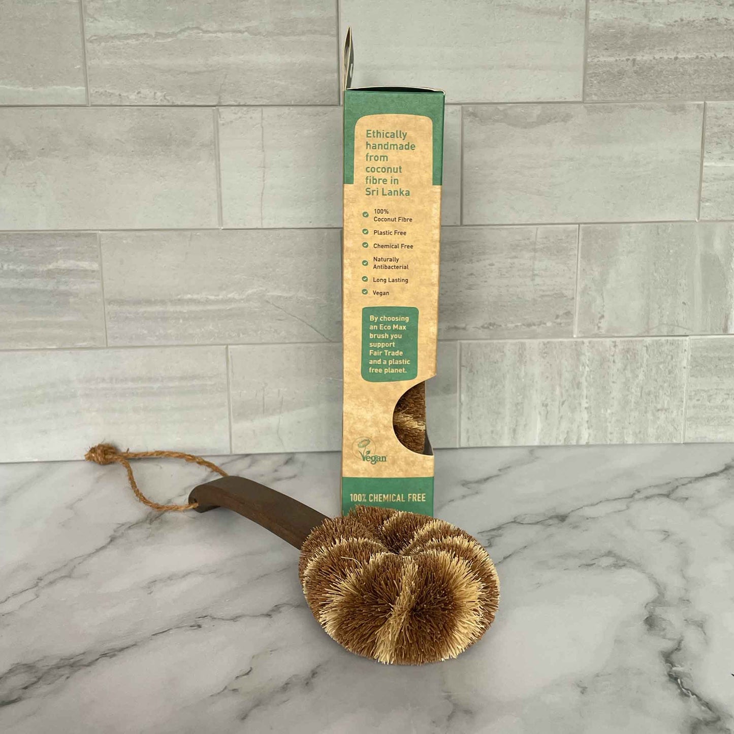 Plastic-free cleaning brush with packaging on a marble surface