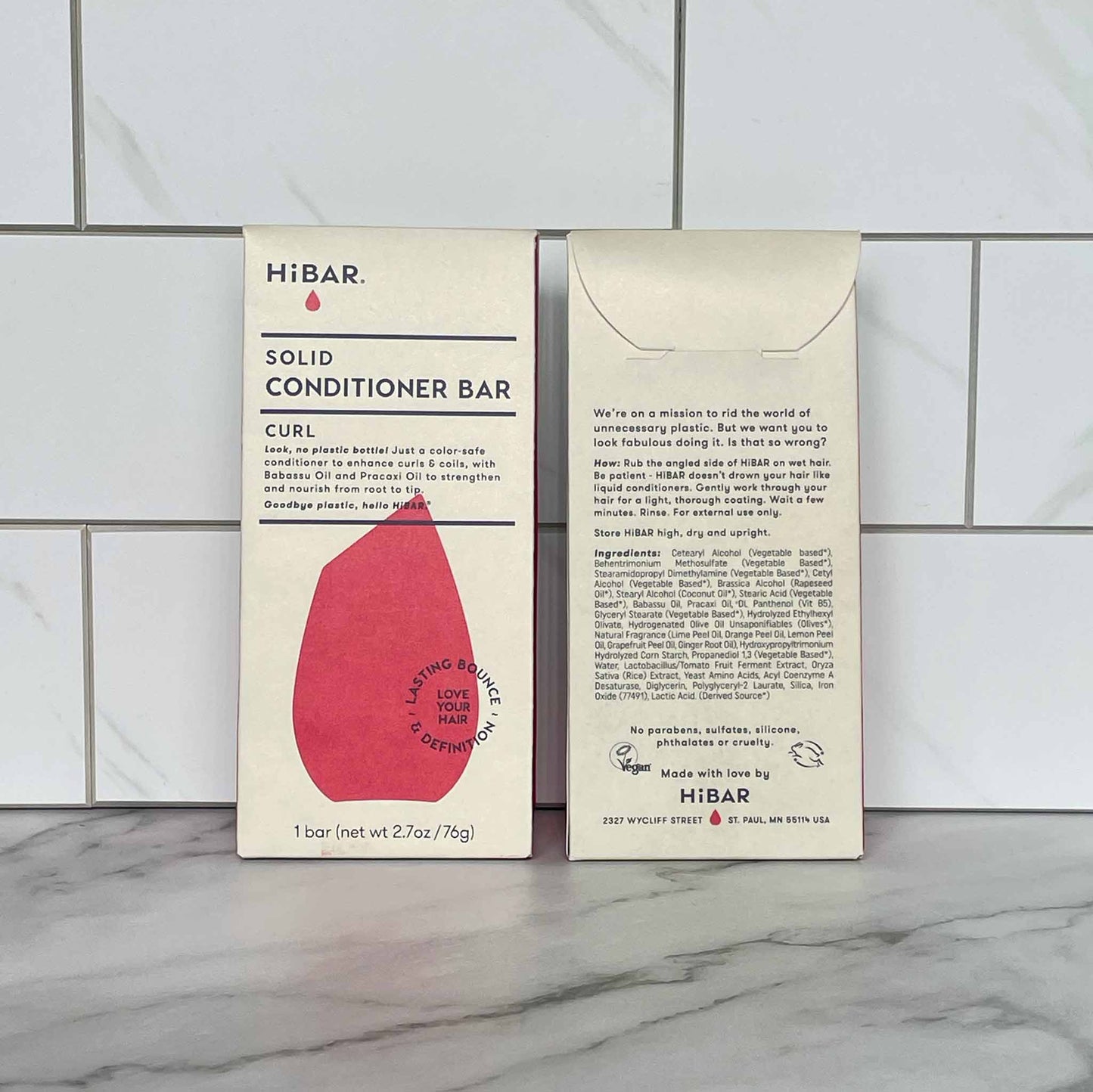 Two HiBAR Curl solid conditioner bar packages on a tiled bathroom floor.