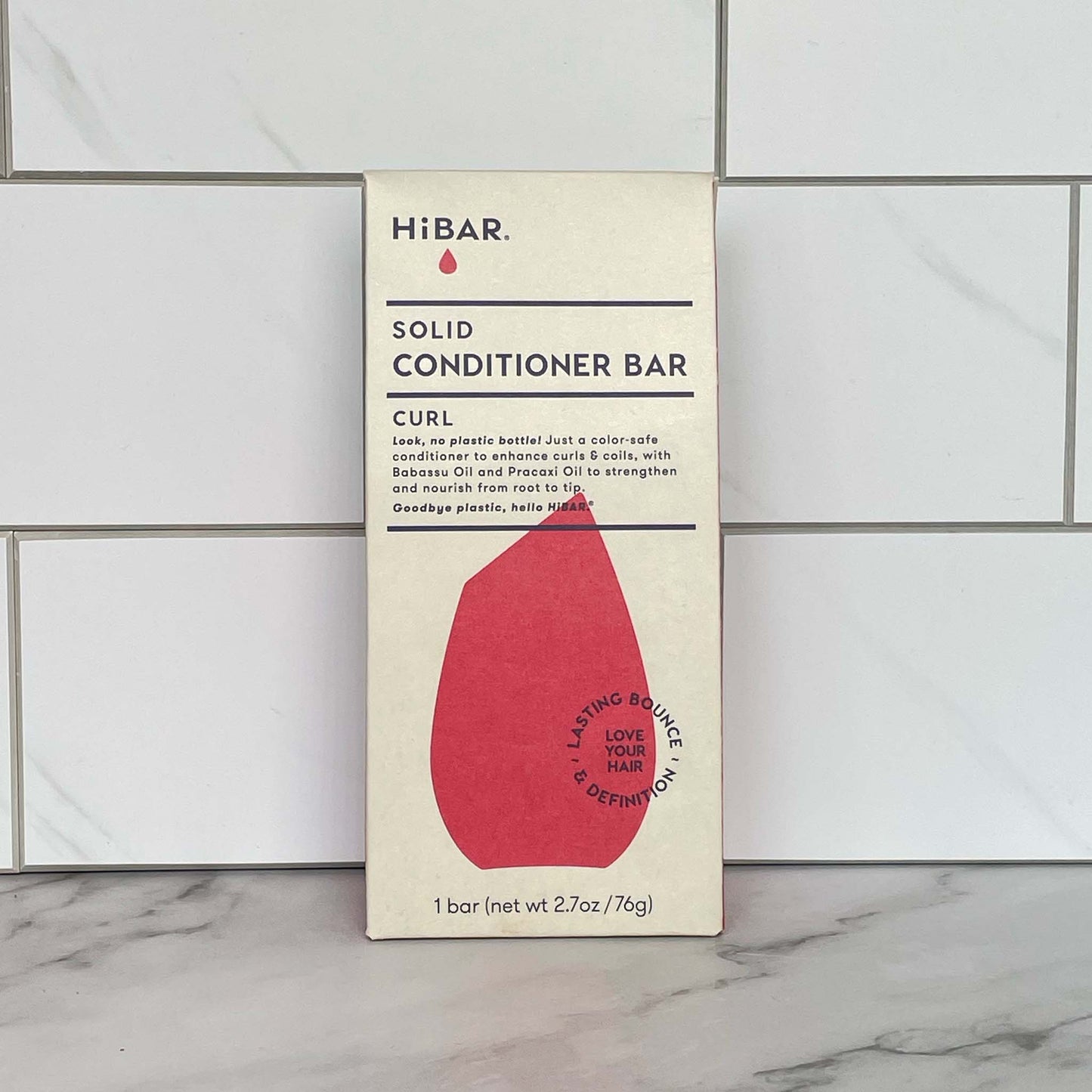 HiBAR Curl solid conditioner bar packaging on a tiled bathroom floor