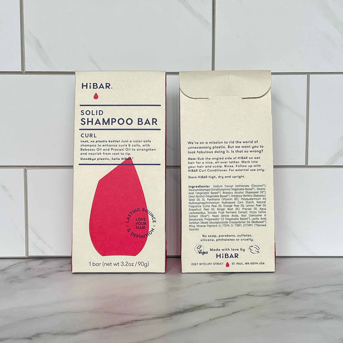 HIBAR Curl solid shampoo bar packaging, front and back, on a tiled bathroom wall.