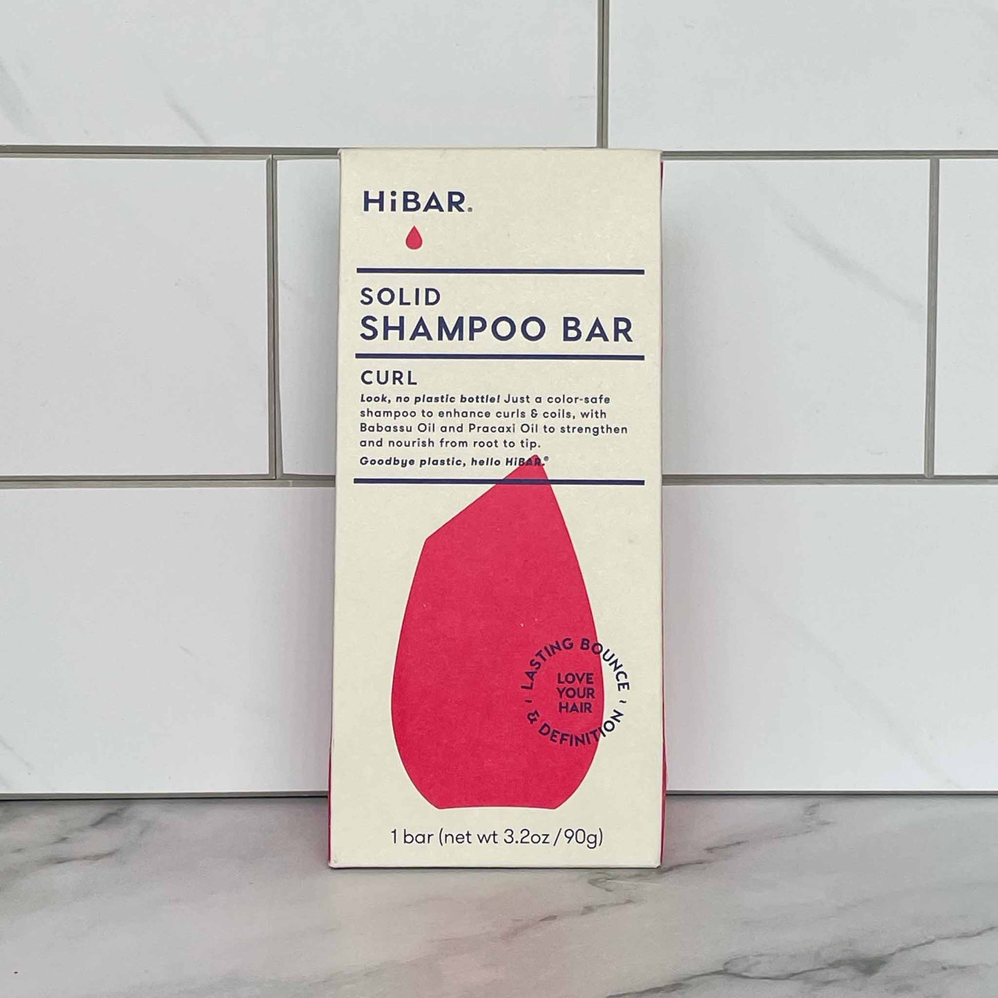 HiBAR Curl solid shampoo bar packaging on a tiled bathroom wall.