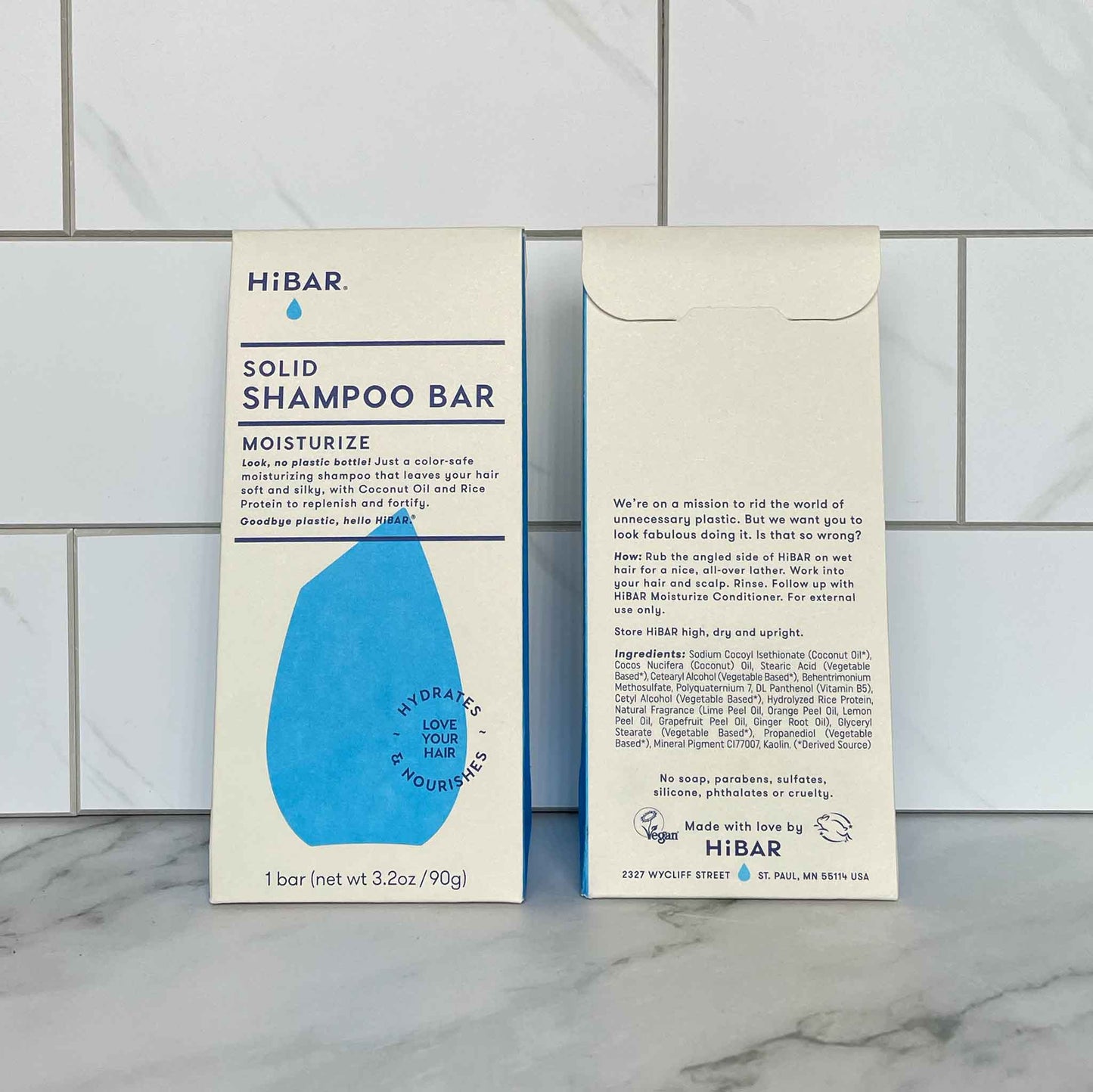 HiBAR Moisturize solid shampoo bar packaging on a tiled bathroom wall.