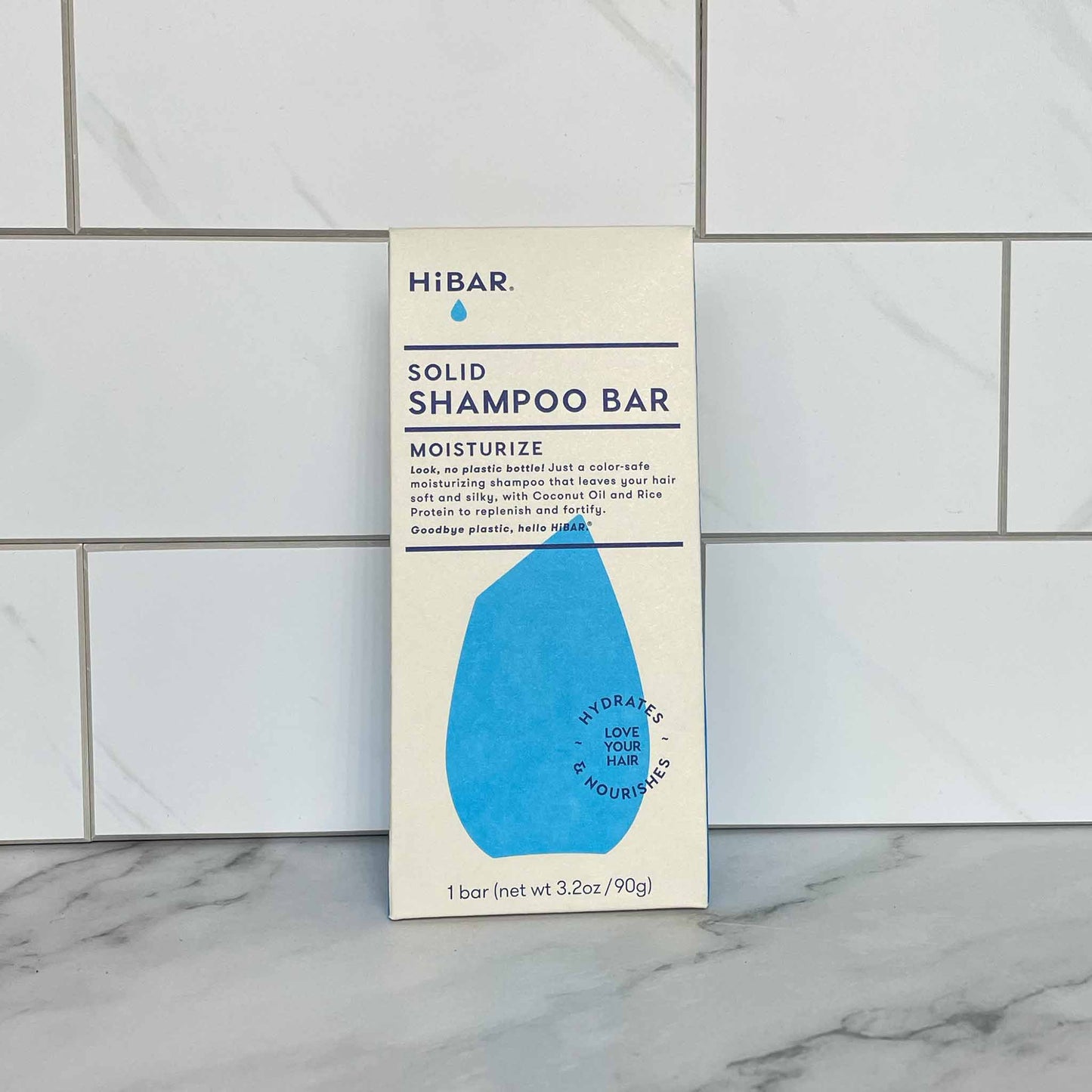 HiBAR Moisturize solid shampoo bar packaging on a tiled bathroom wall