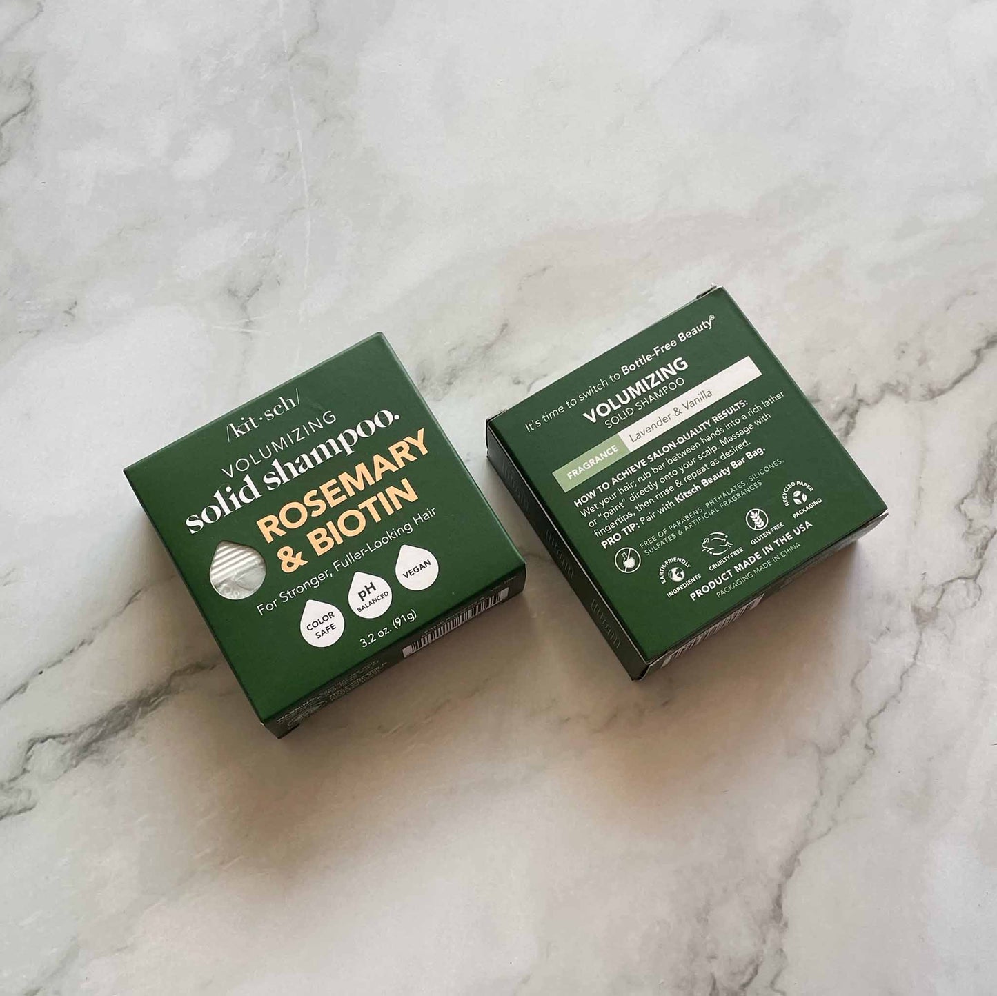 Two green boxes of Kitsch volumizing solid shampoo on a marble surface