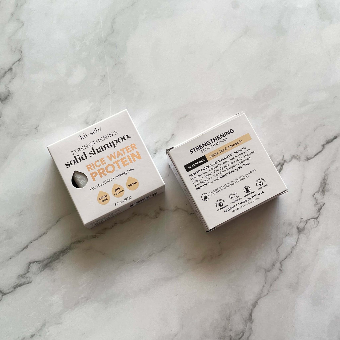 Two boxes of Kitsch Strengthening Solid Shampoo on a marble surface