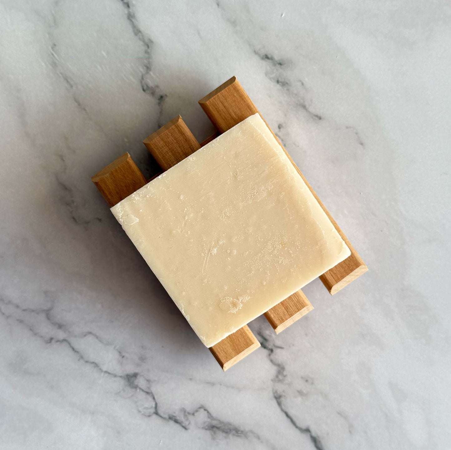 Kitsch shave butter bar on a wooden soap dish against a marble background