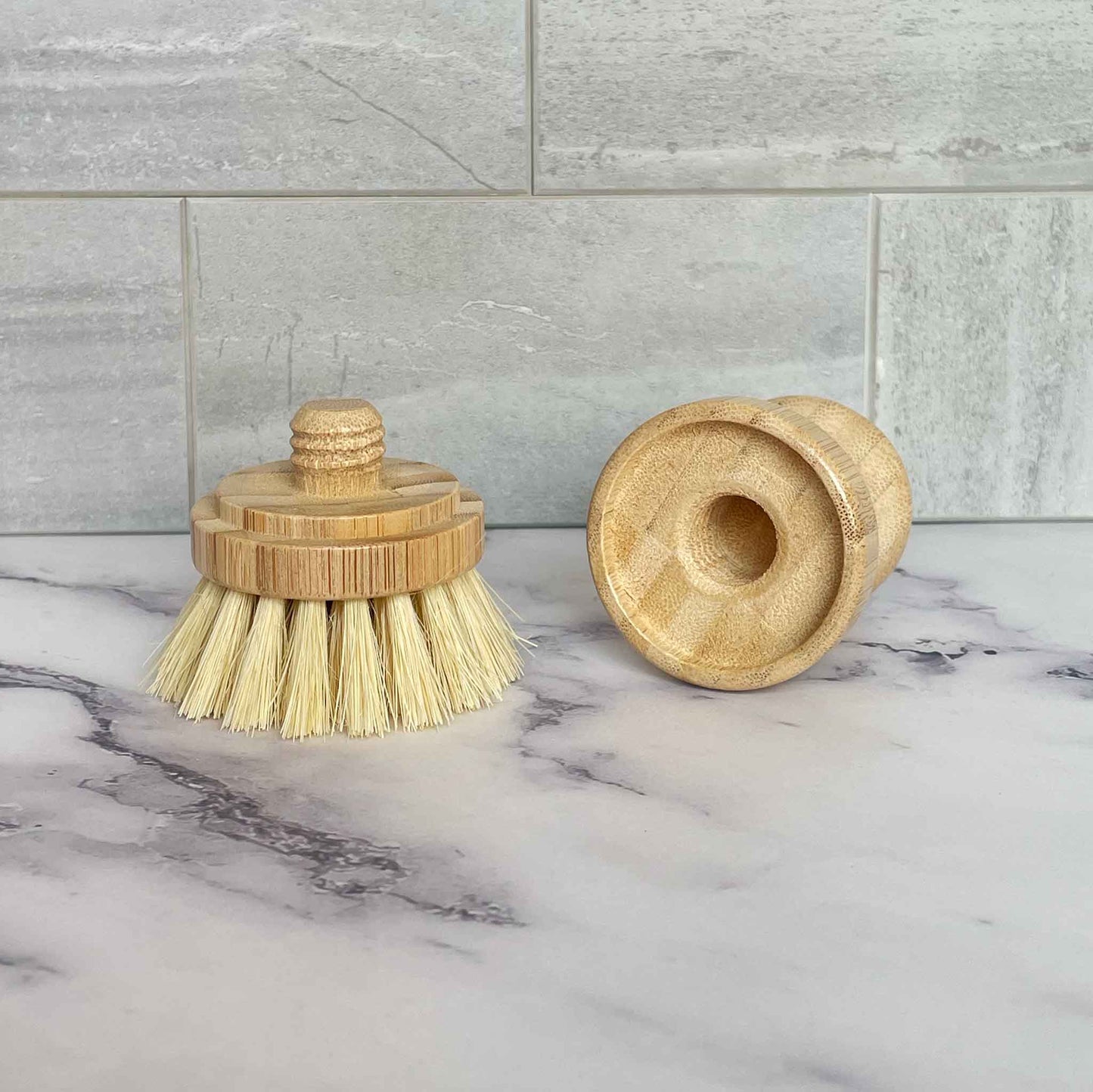 Bamboo scrubbing brush with sisal bristles on a marble surface with a tiled wall background