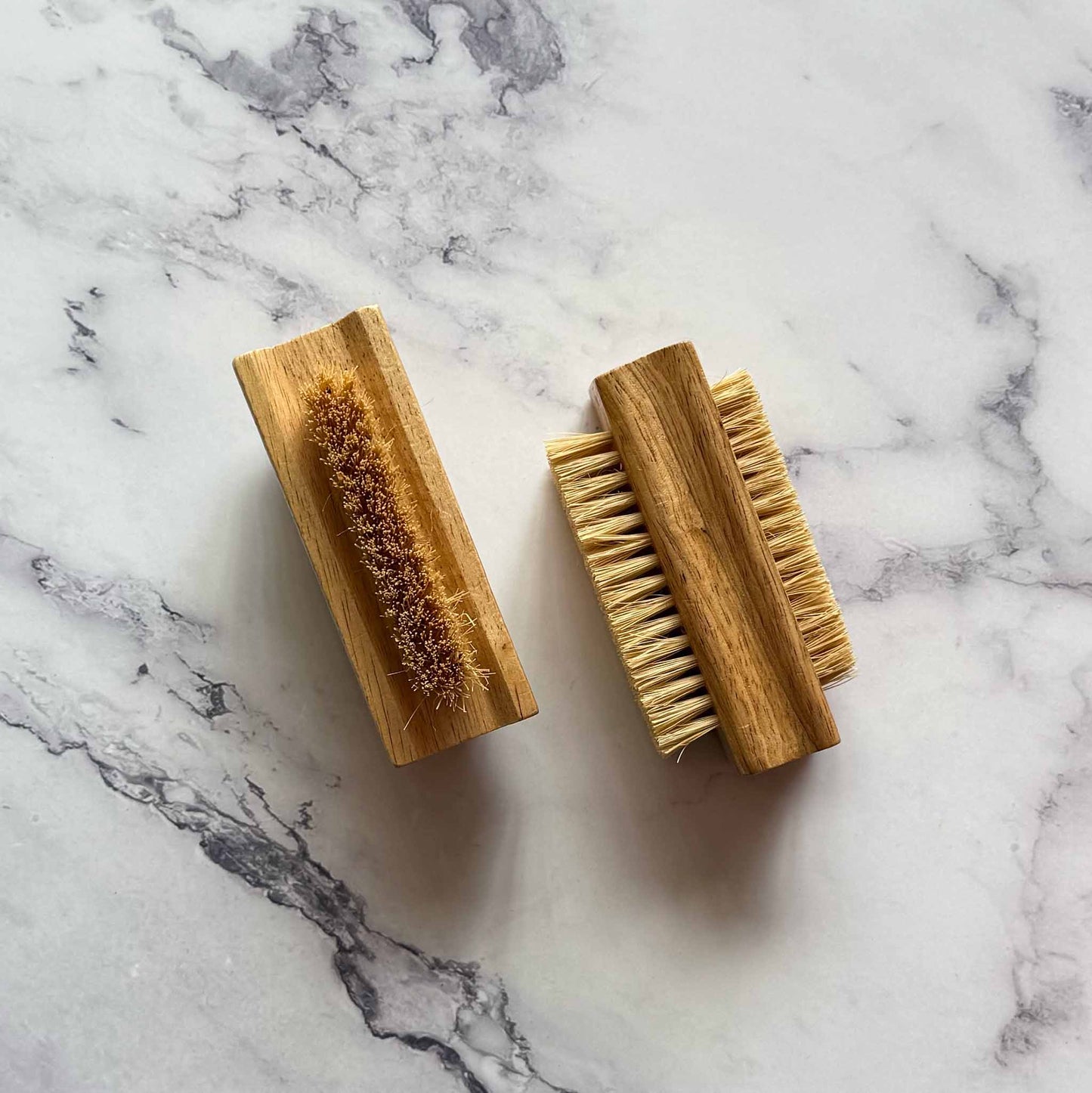 Two wooden brushes with bristles on a marble surface
