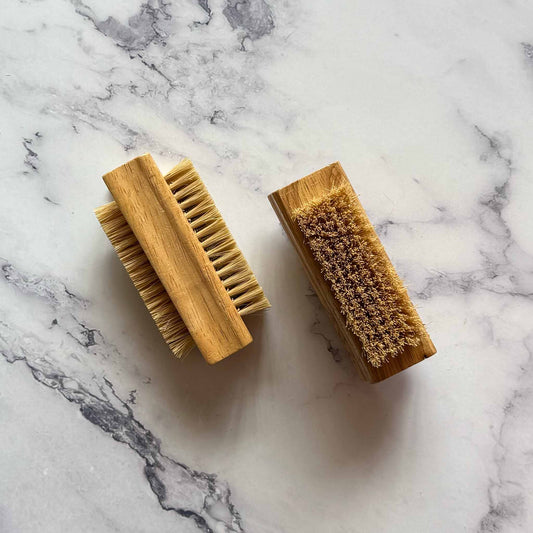 Two wooden brushes with bristle heads on a marble surface