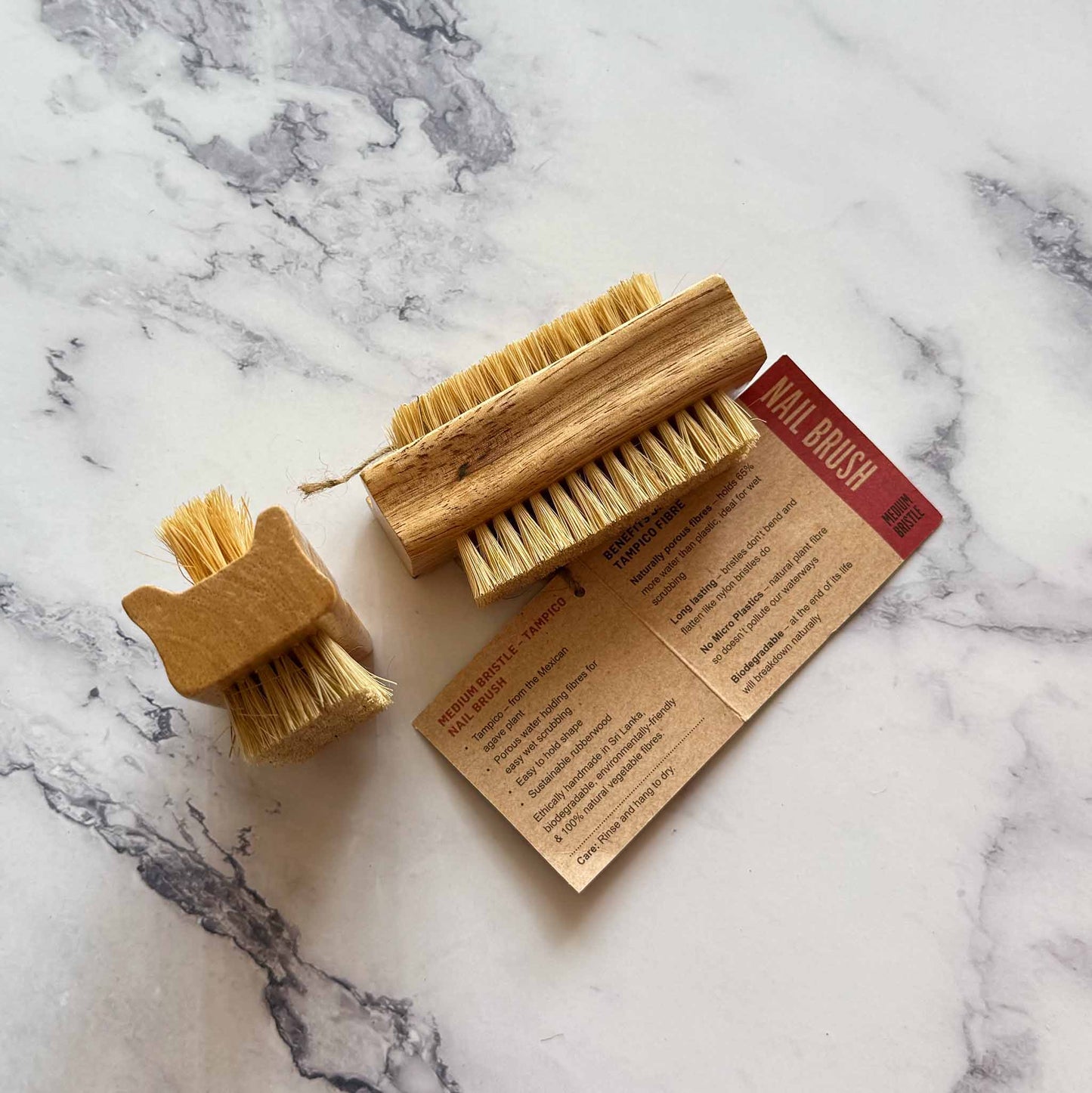 Two wooden nail brushes on a marble surface