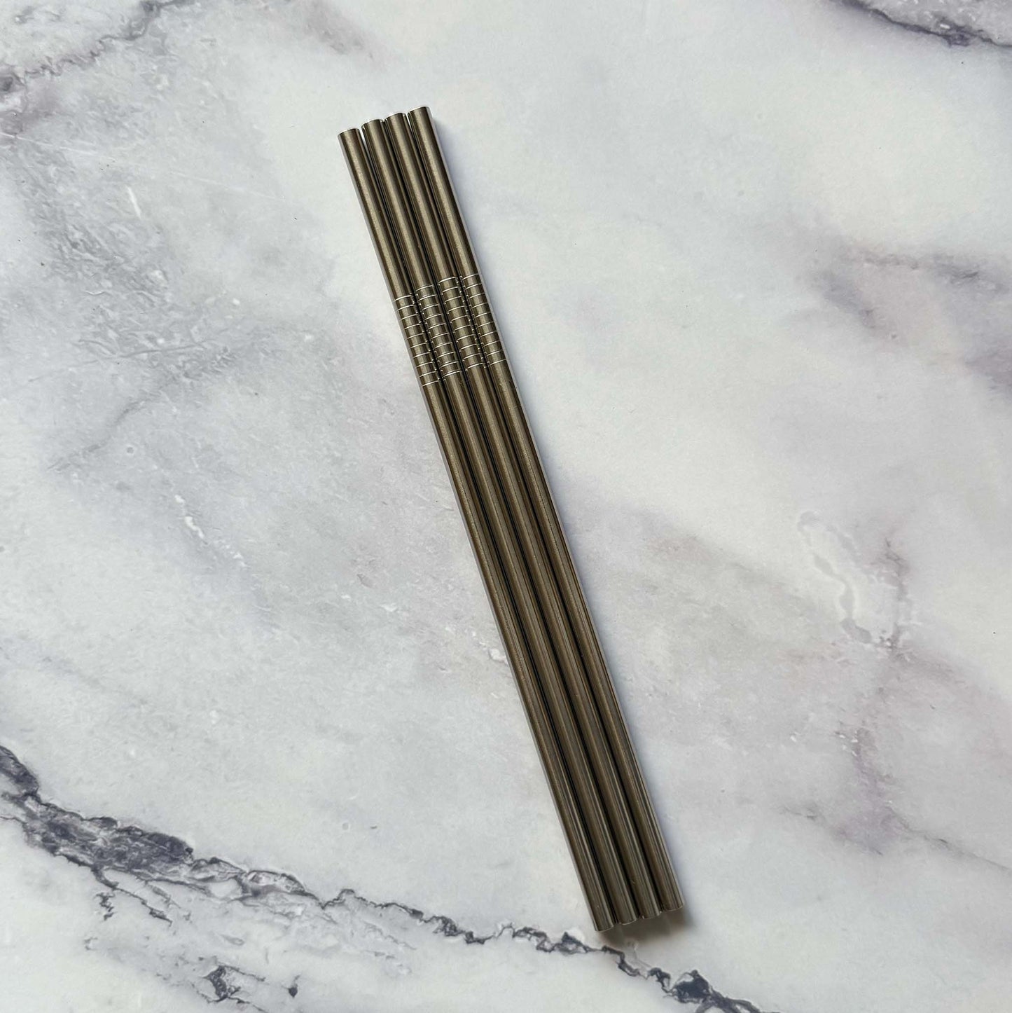 Four Reusable 8.5 Inch Straight Stainless Steel Straws on marble surface