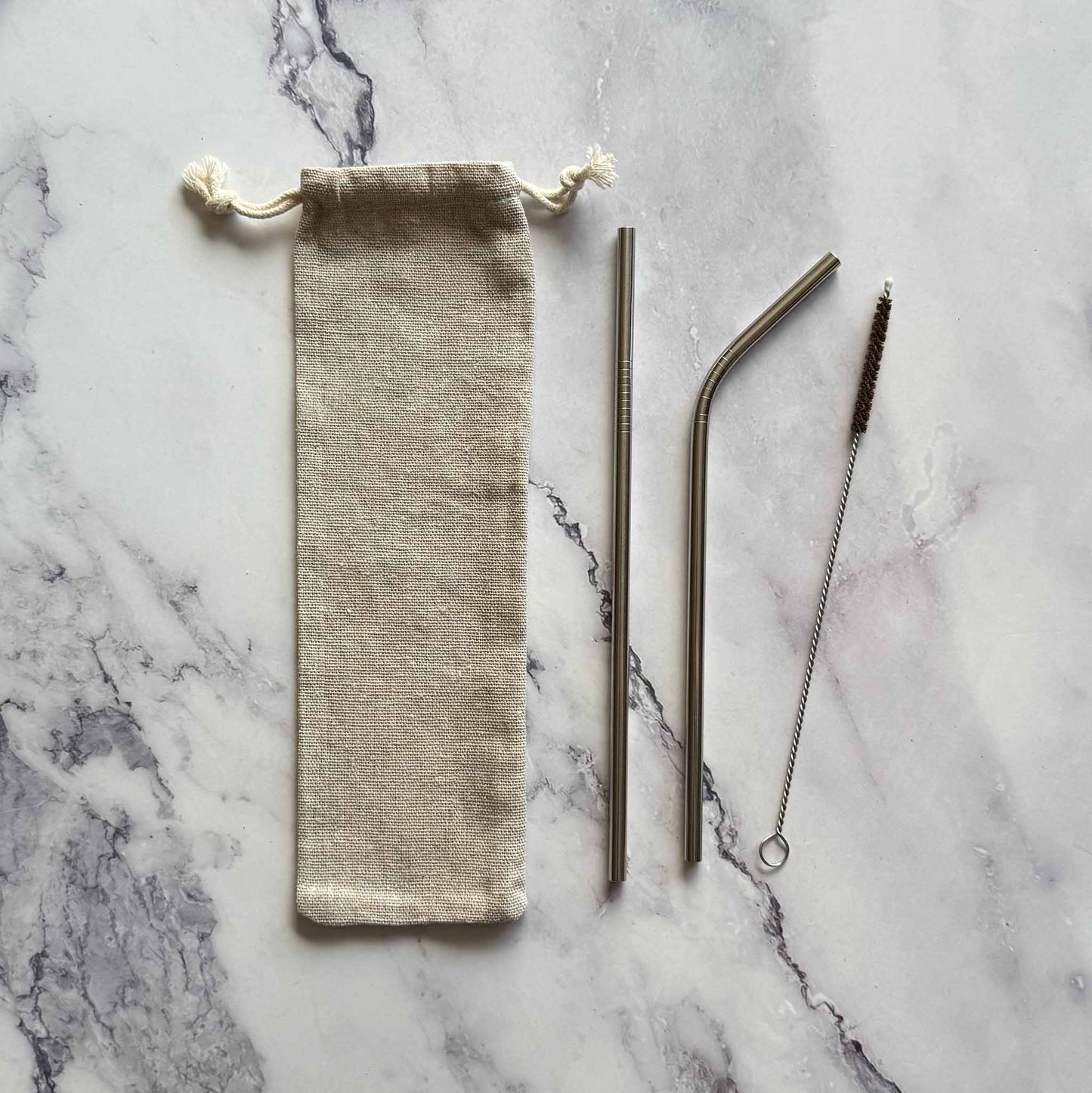 Set of reusable straws with a carrying bag on a marble surface