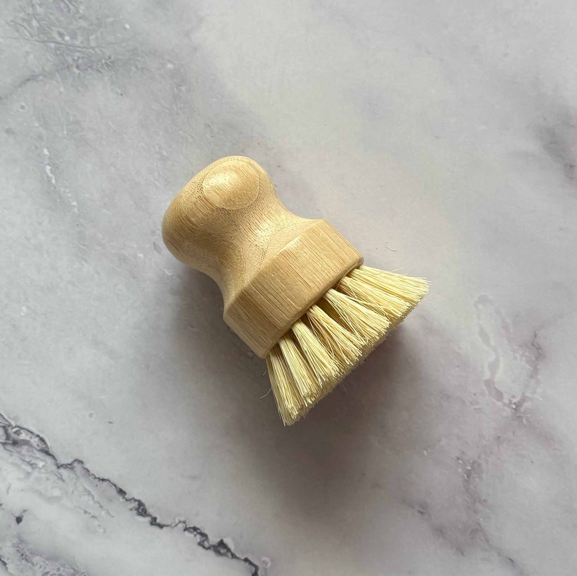 Bamboo dish brush with sisal bristles on a marble surface