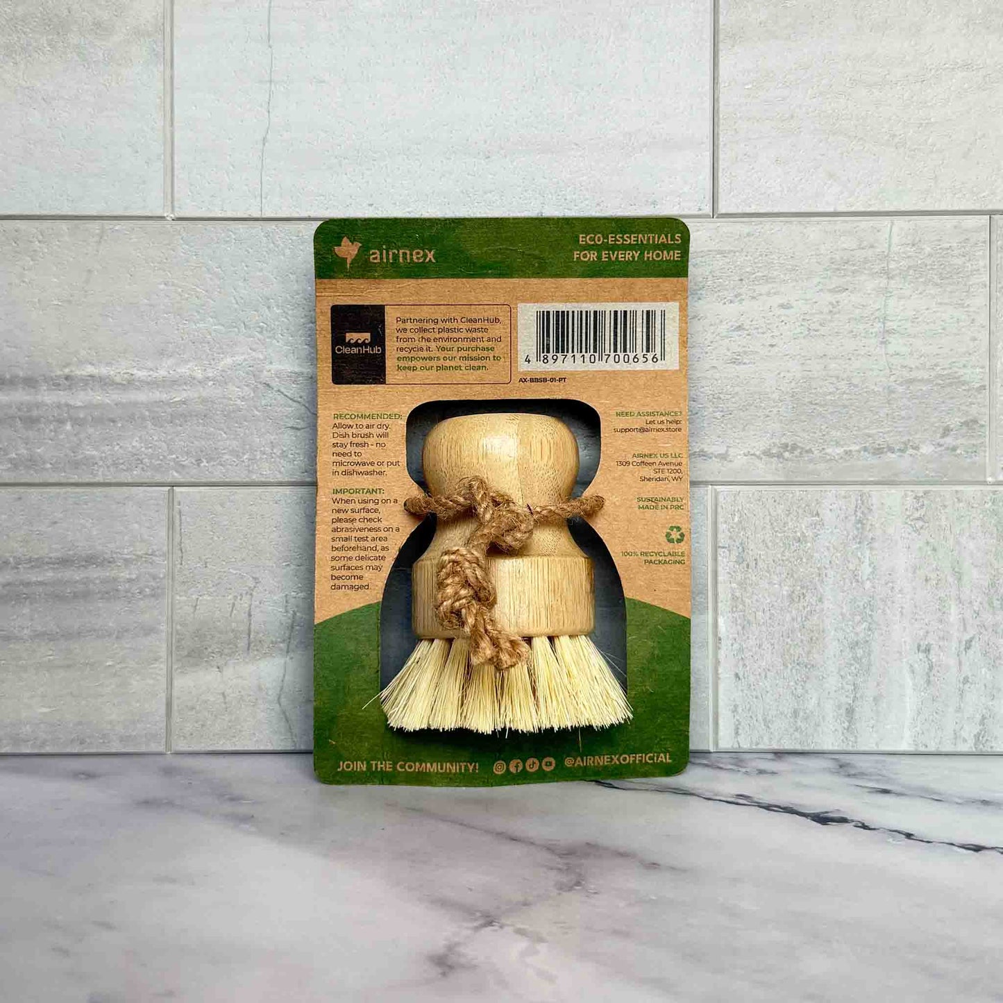 Bamboo Dish Brush with packaging on a marble surface and tiled wall background