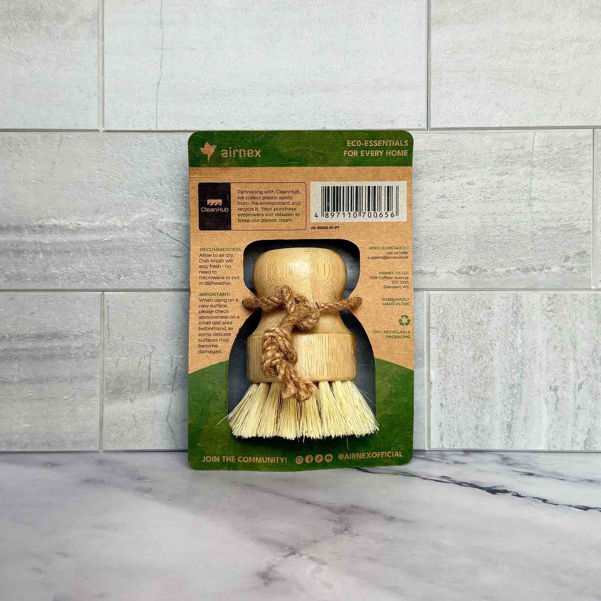 Bamboo Dish Brush with packaging on a marble surface and tiled wall background