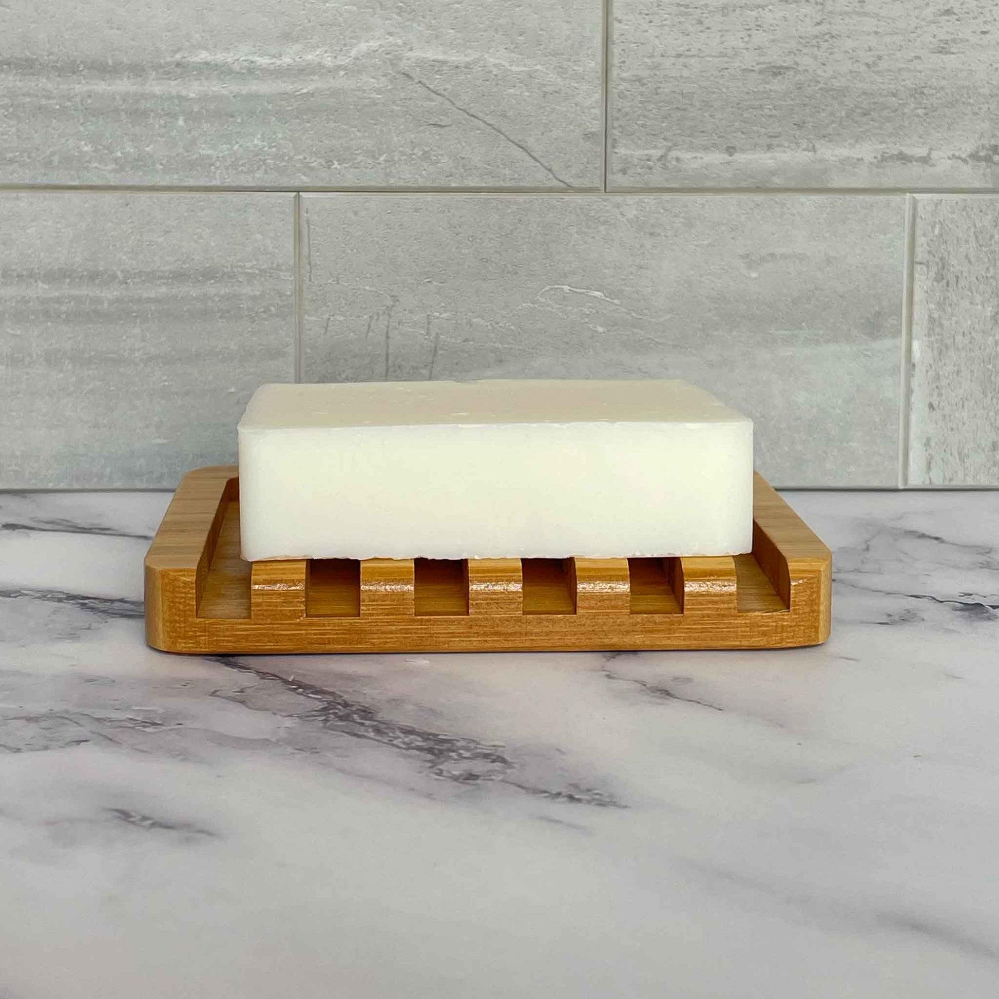 Bar of soap on a bamboo soap dish with a marble and tile background