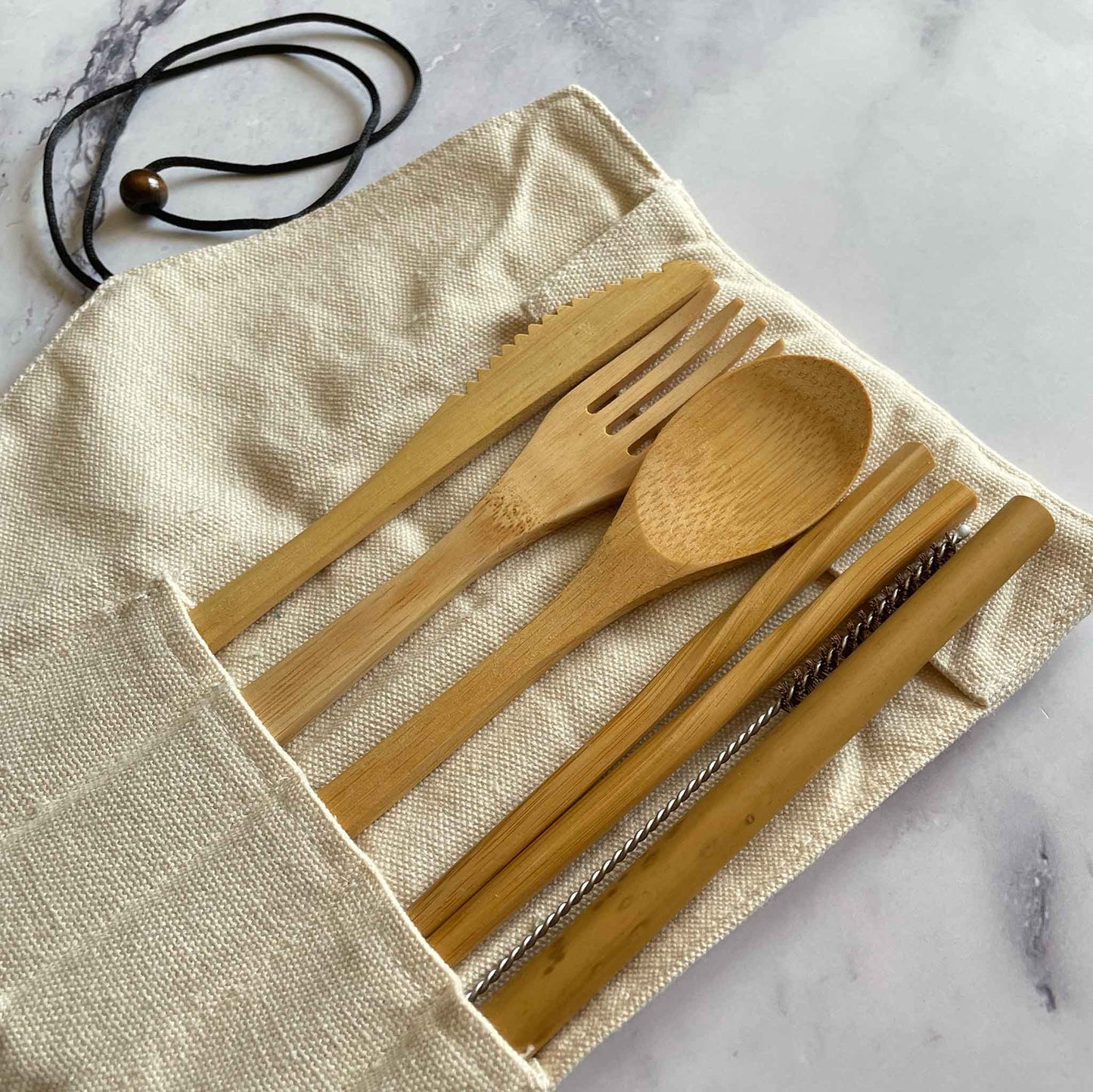 Bamboo Travel Cutlery Set including fork, spoon, knife, straw, straw cleaner, and chopsticks inside the cotton pouch