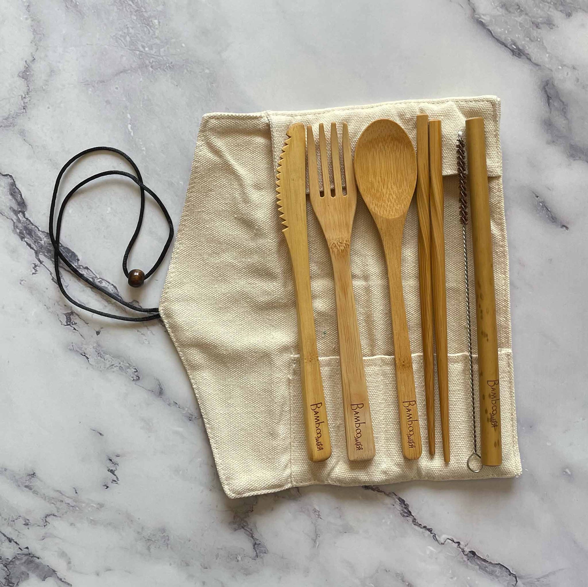 Bamboo Travel Cutlery Set including fork, spoon, knife, straw, straw cleaner, and chopsticks on the cotton pouch