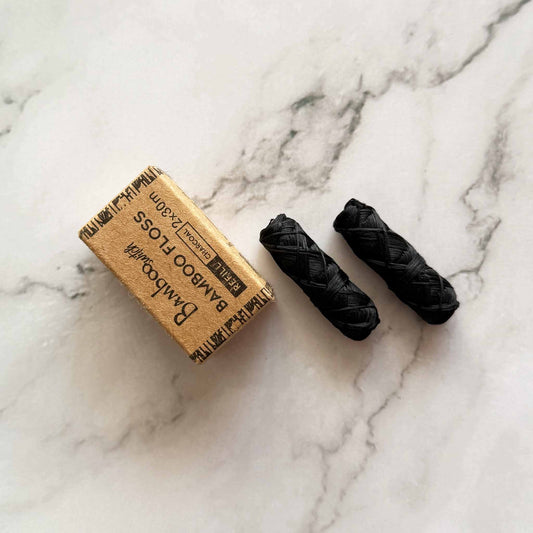 Two Charcoal bamboo floss refill with packaging box on a marble surface
