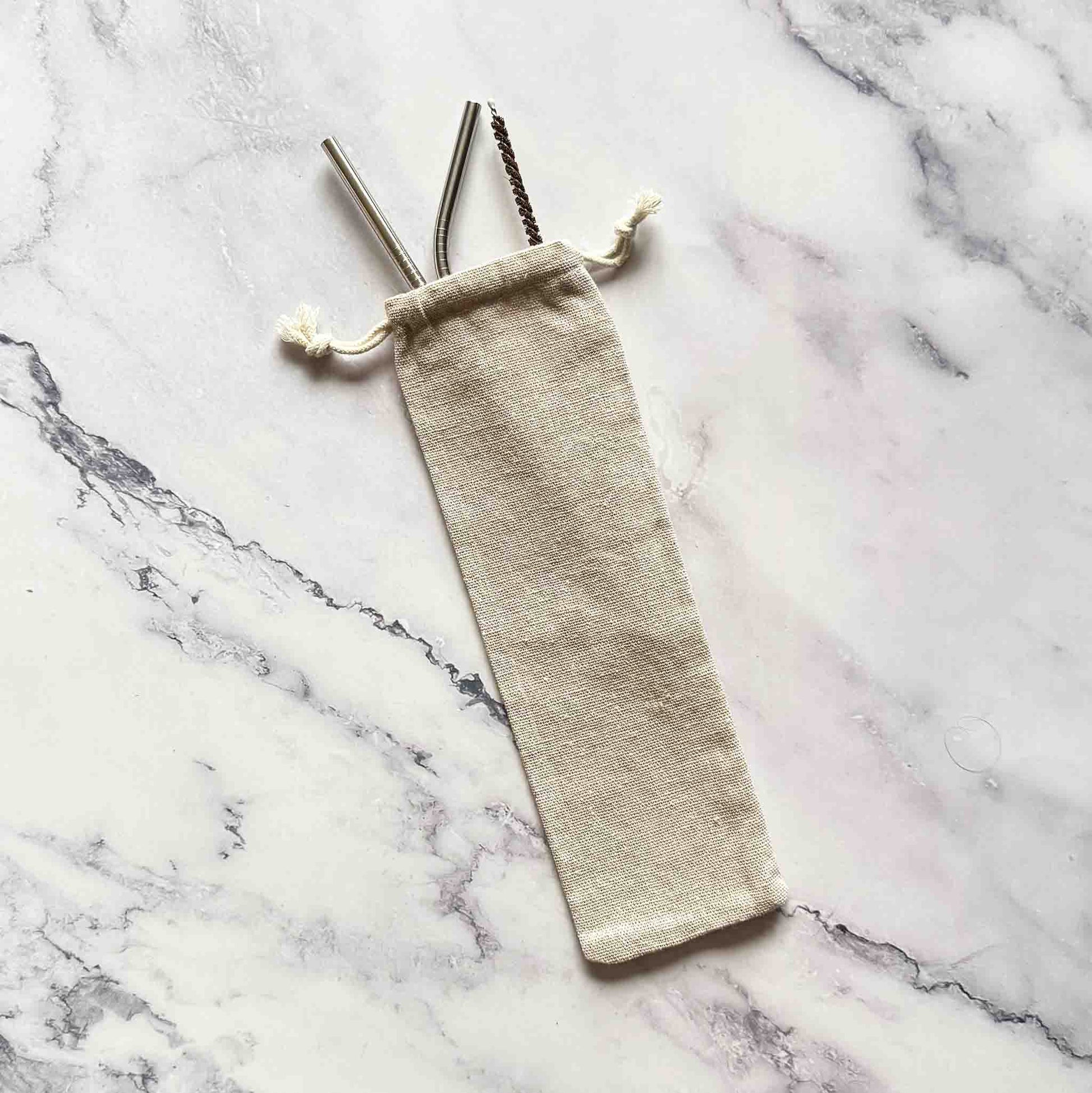 Cotton bag with straws on marble surface