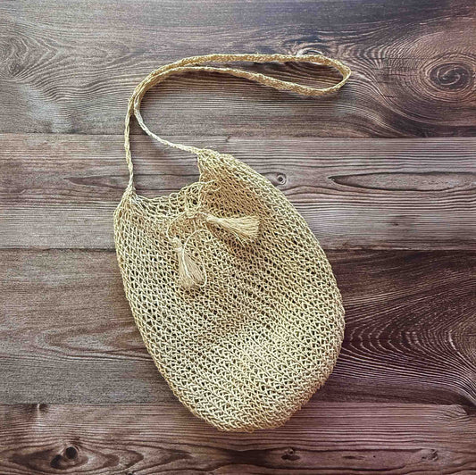 Handwoven Cumare Fiber Mochila  with a strap on a wooden surface