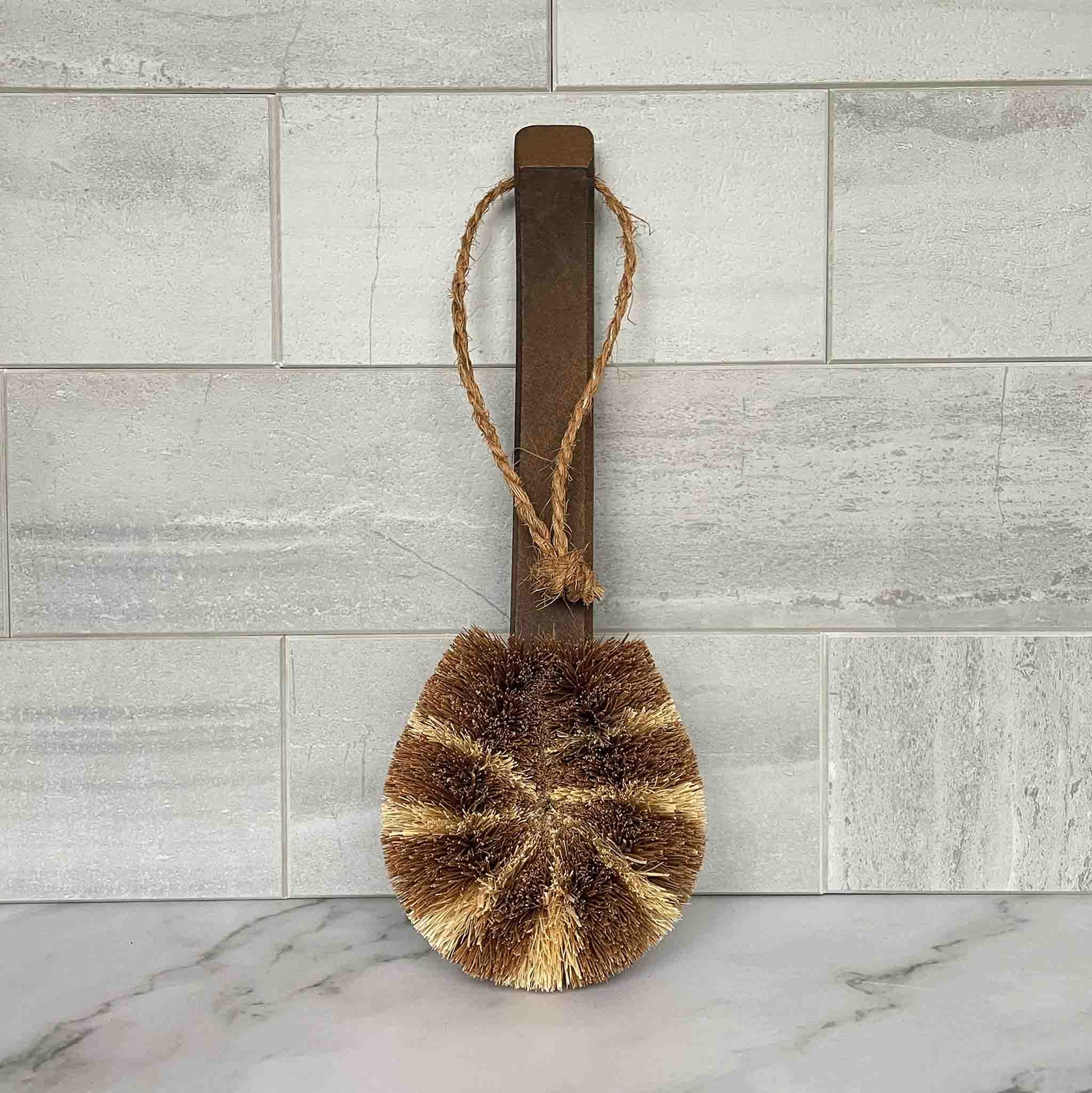 Bristle brush with a wooden handle on a marble surface with a tiled wall background