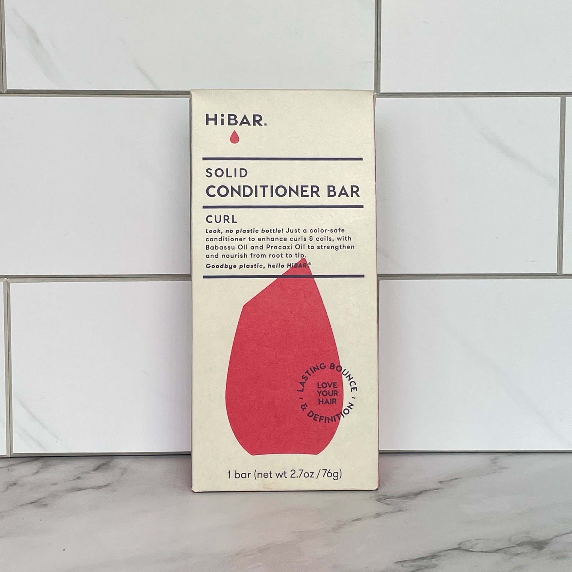 HiBAR Curl solid conditioner bar packaging on a tiled bathroom floor