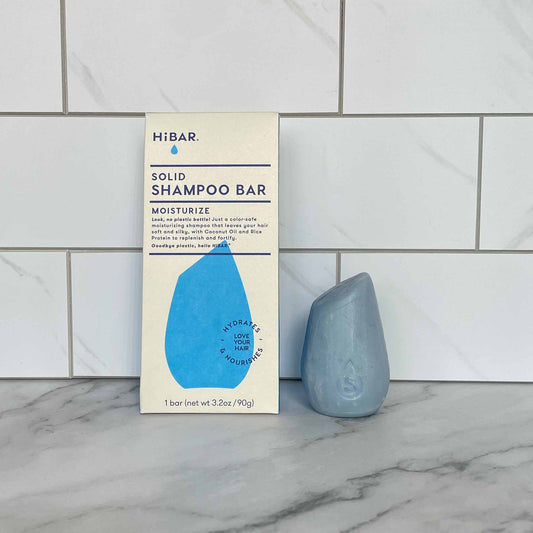 HiBAR Moisturize Solid shampoo bar with packaging on a marble surface against a tiled wall background