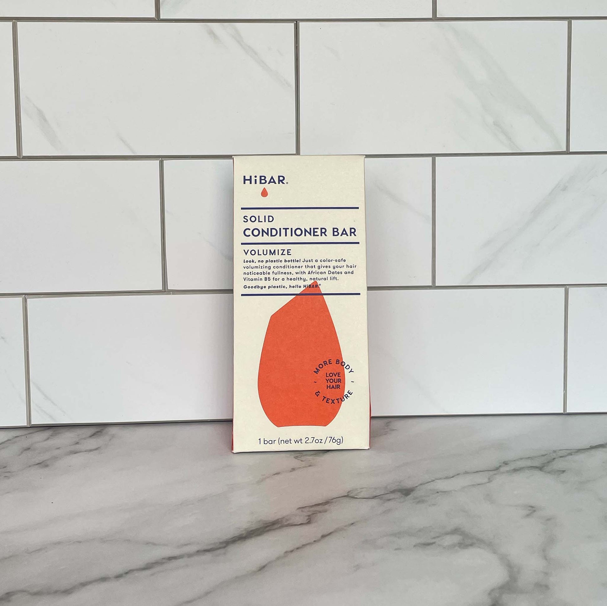 HiBAR Volumize solid conditioner bar packaging on a marble surface with tiled wall background