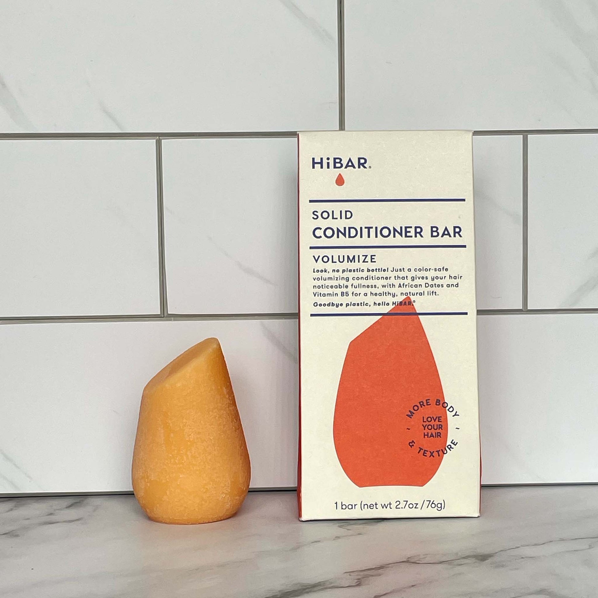 HiBAR Volumize conditioner bar and its packaging on a tiled bathroom wall background
