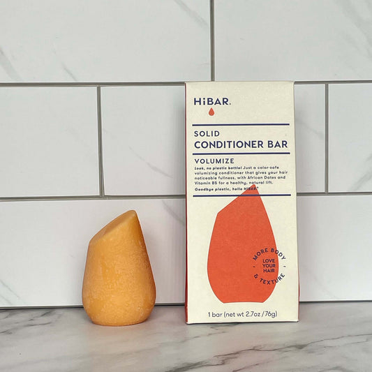 HiBAR Volumize conditioner bar and its packaging on a tiled bathroom wall background