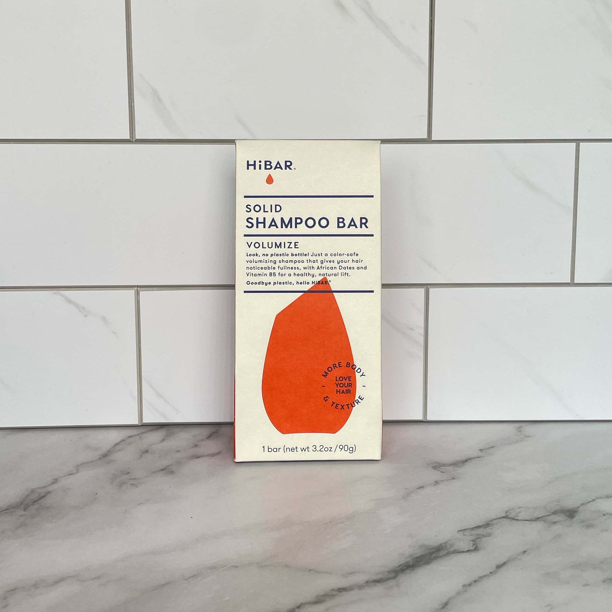 HiBAR Volumize solid shampoo bar packaging on a marble surface with tiled wall background