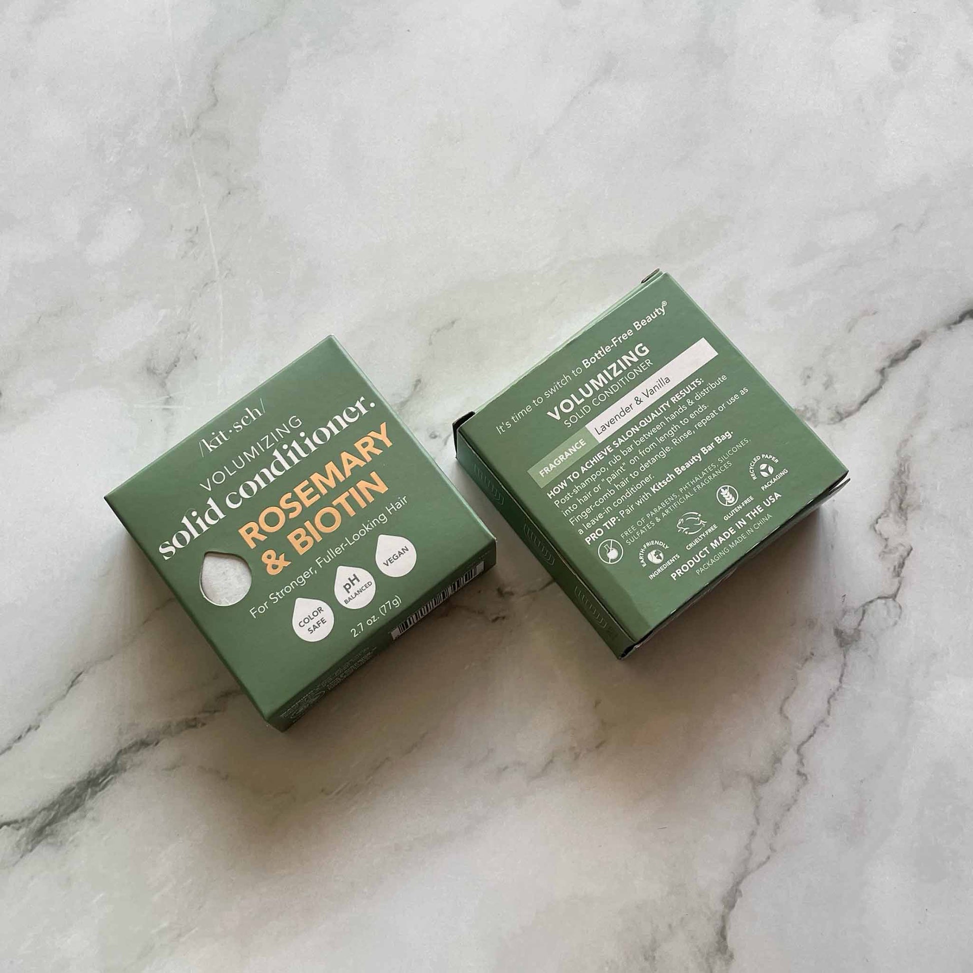 Two green boxes of Kitsch volumizing solid conditioner with rosemary and biotin on a marble surface.