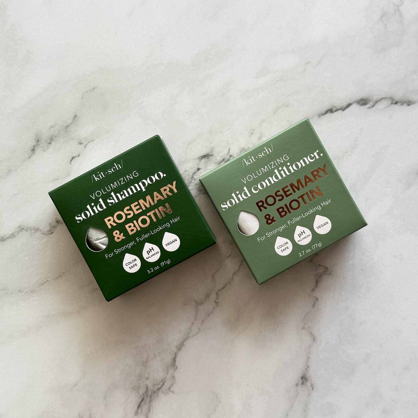 Two green boxes of KitSch solid shampoo and conditioner on a marble surface