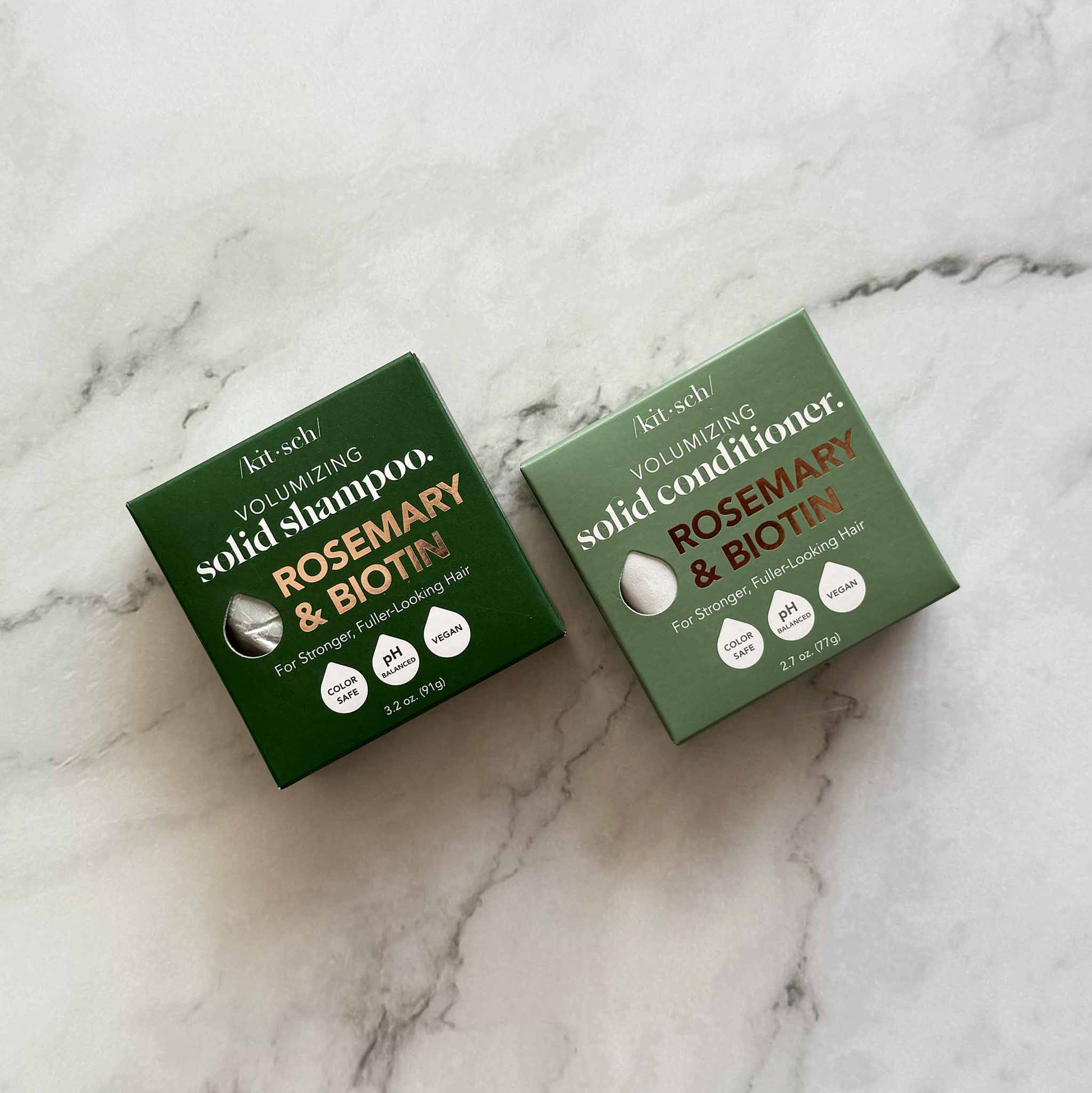 Two green boxes of KitSch solid shampoo and conditioner on a marble surface