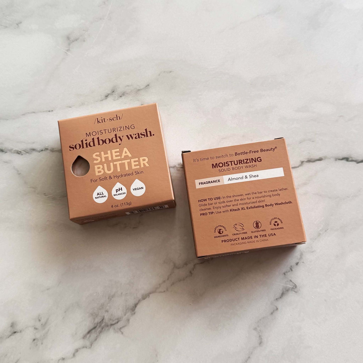 Two boxes of Kitsch shea butter solid body wash bars on a marble surface