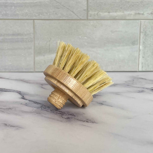 Bristle brush with bamboo handle on a marble surface with tiled wall background