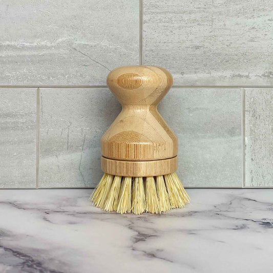 Bamboo dish brush on a marble surface with tiled wall background