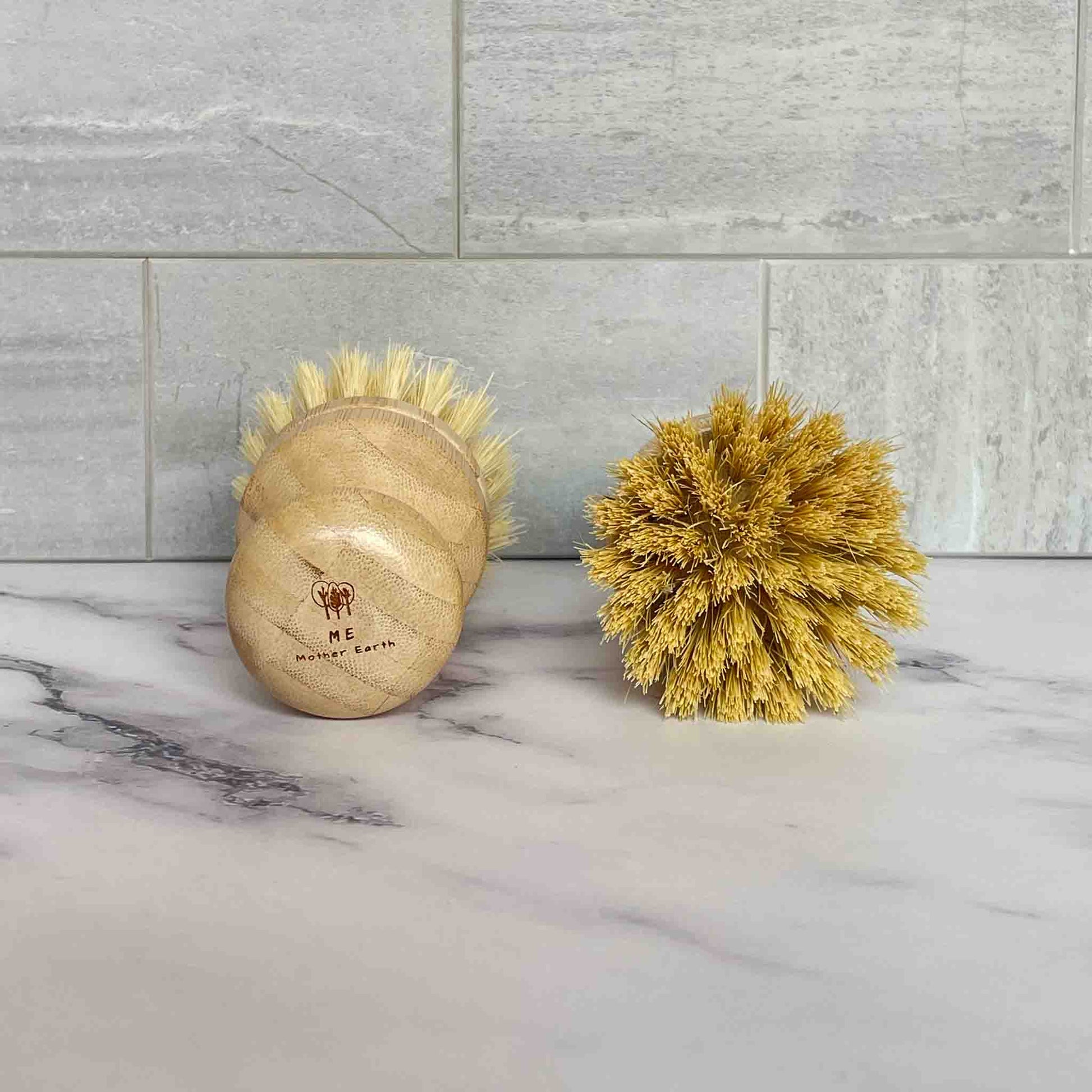 Bamboo brushes with sisal bristles on a marble surface with tiled wall background.