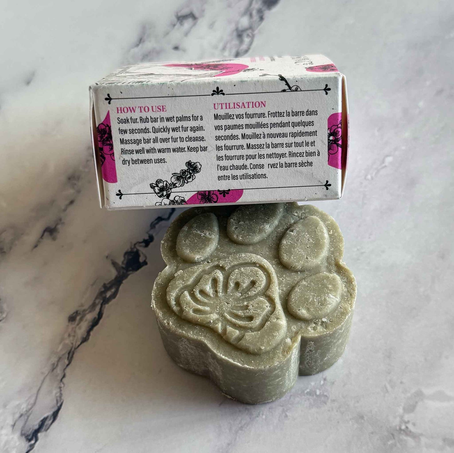 Pet Shampoo Bar on marble surface with box on the side showing How-To use instructions