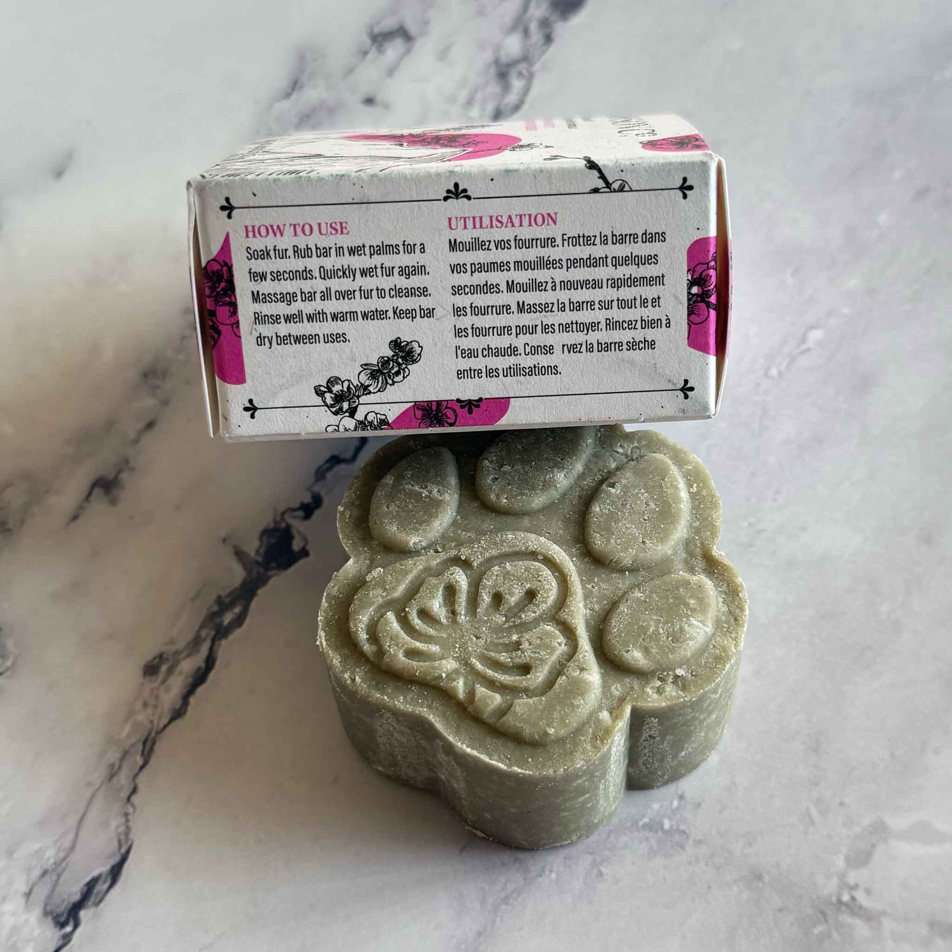 Pet Shampoo Bar on marble surface with box on the side showing How-To use instructions
