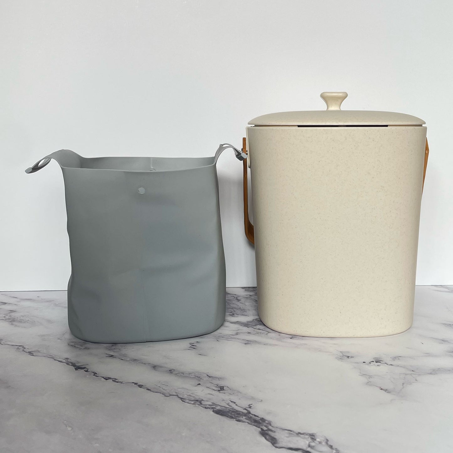 Silicone Compost Bin Liner next to a natural compost bin on a marble surface