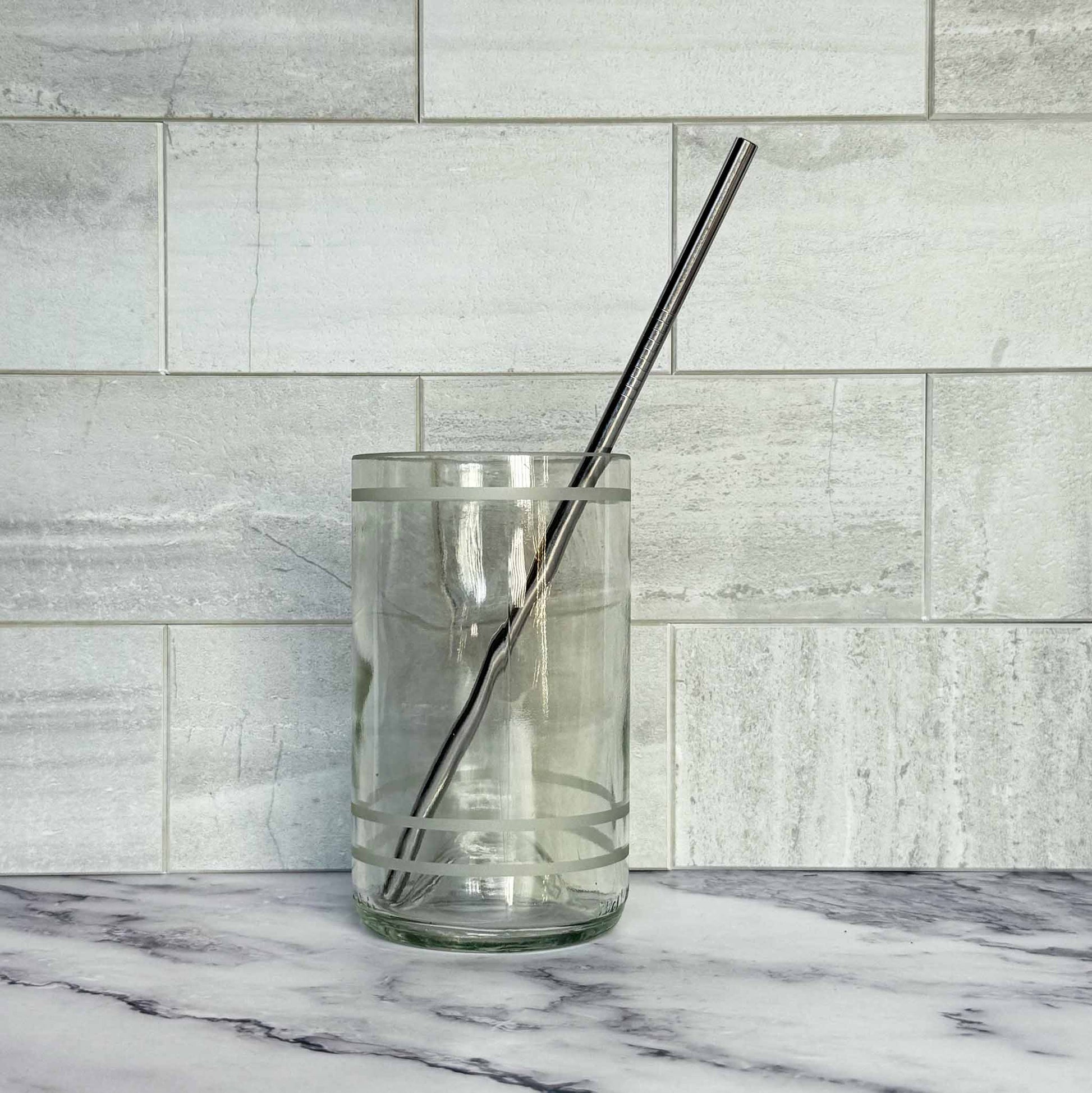 Reusable 8.5 Inch Straight Stainless Steel Straw in a glass against a tiled background
