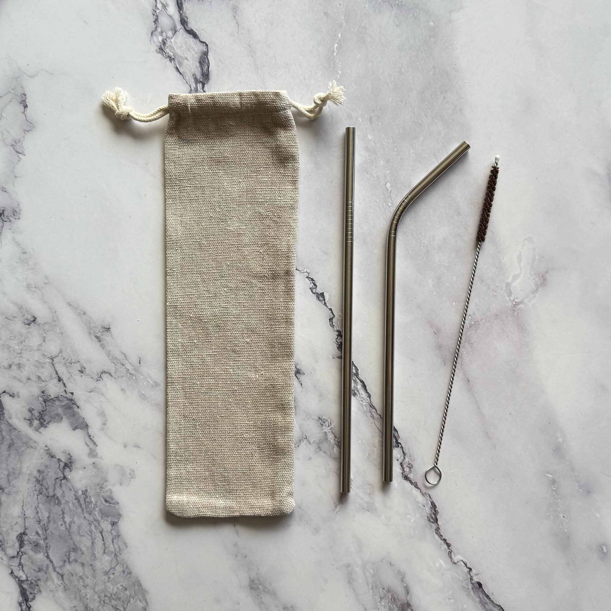 Set of reusable straws with a carrying bag on a marble surface