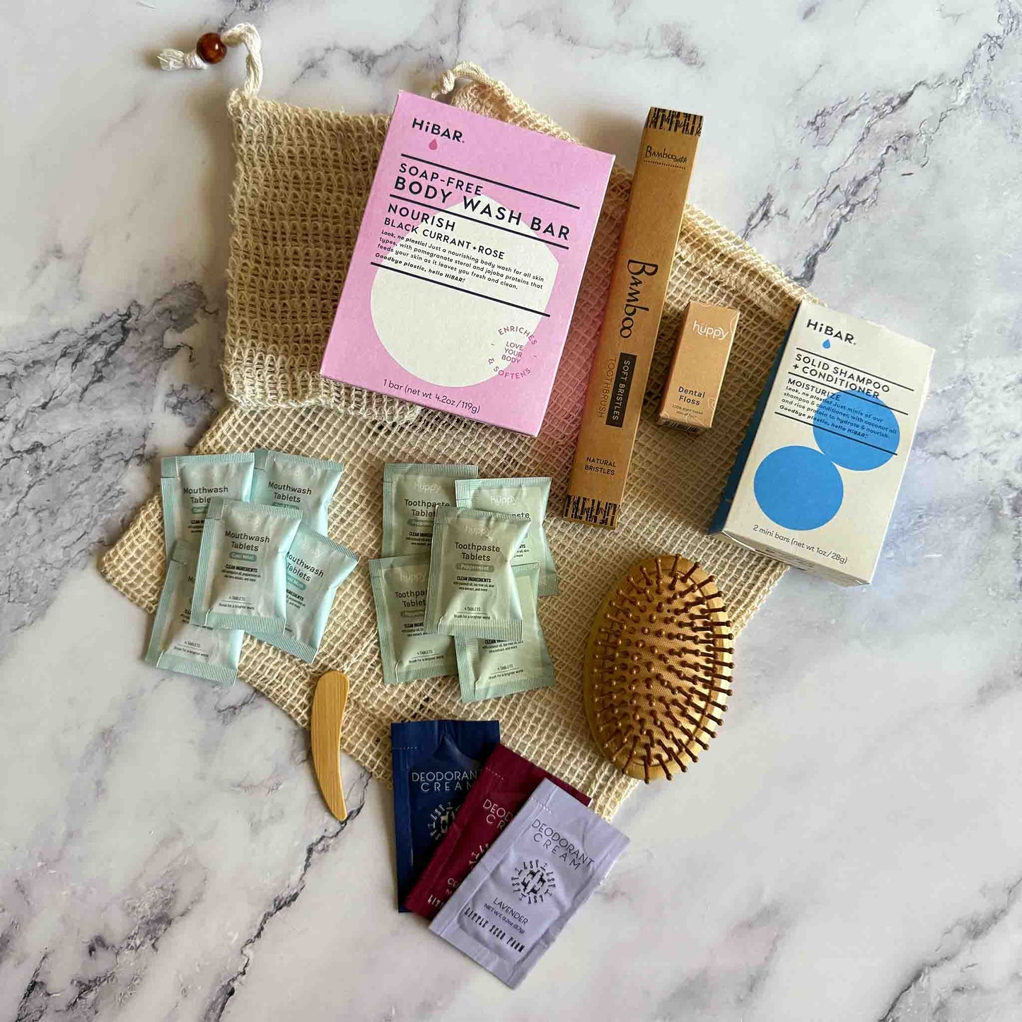 Collection of zero-waste products including a soap-free body wash bar, shampoo bars, and other personal care items on a marble surface.