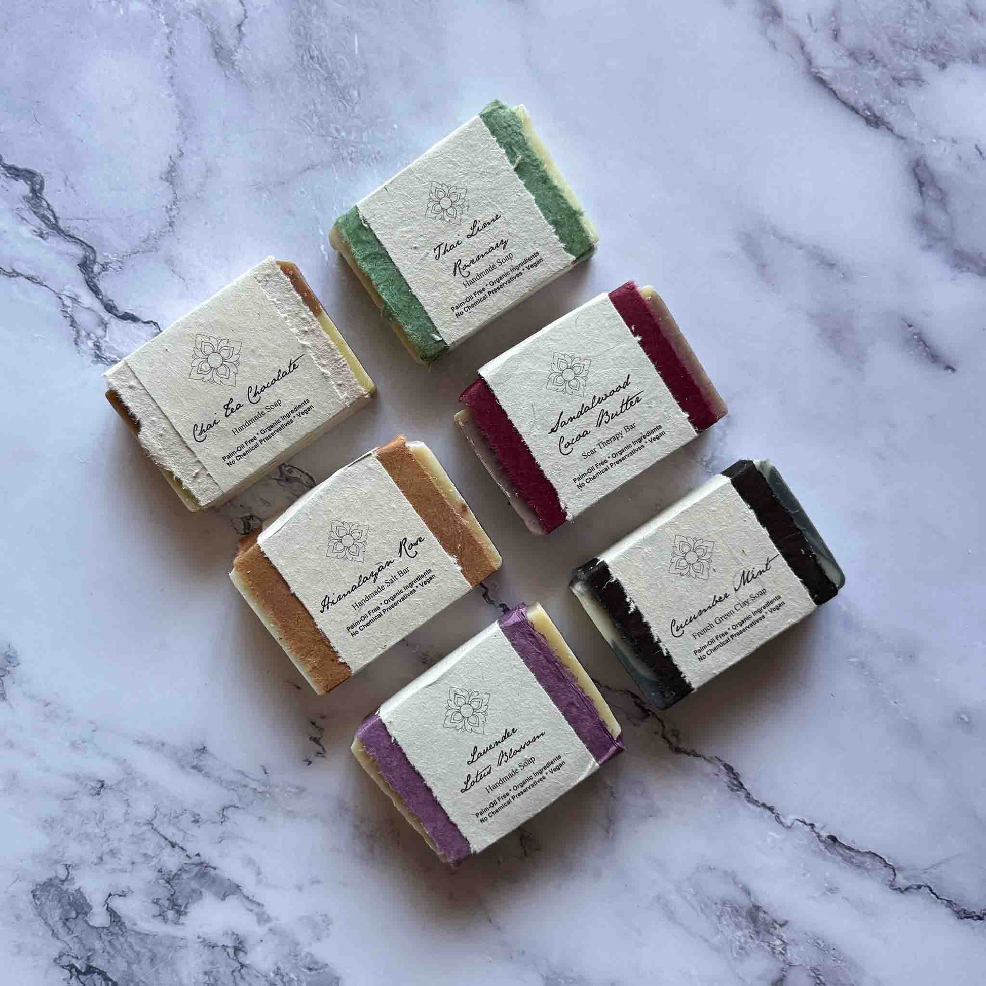 Set of six handmade soap bars with labels on a marble surface